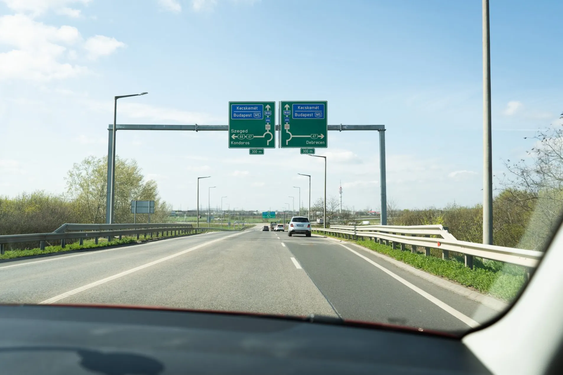 View from the driver's seat on the M44 motorway in Hungary showing junction signs for Kecskemét, Budapest via M5, Szeged, and Debrecen, photographed by Mattijs Wijnmalen at Easter 2026.