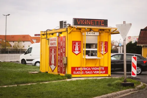 Yellow Hungary e-matrica vignette sales kiosk with LED display showing VIGNETTE and cassa window at border crossing