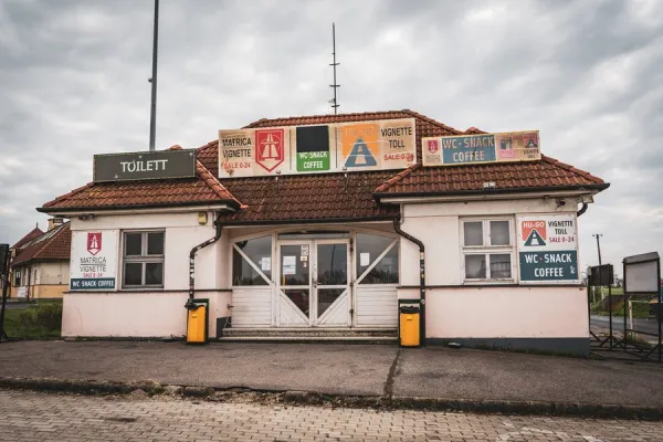 A roadside vignette sales office at the Rajka border crossing into Hungary, displaying Matrica Vignette and HU-GO toll signs with 0–24 hour service, WC, snacks and coffee, photographed by Noemi Karacsonyi.